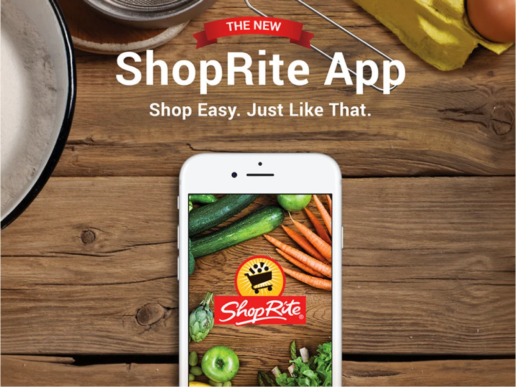“The new ShopRite App: Shop easy. Just like that.” A phone on a wooden table surrounded by vegetables.